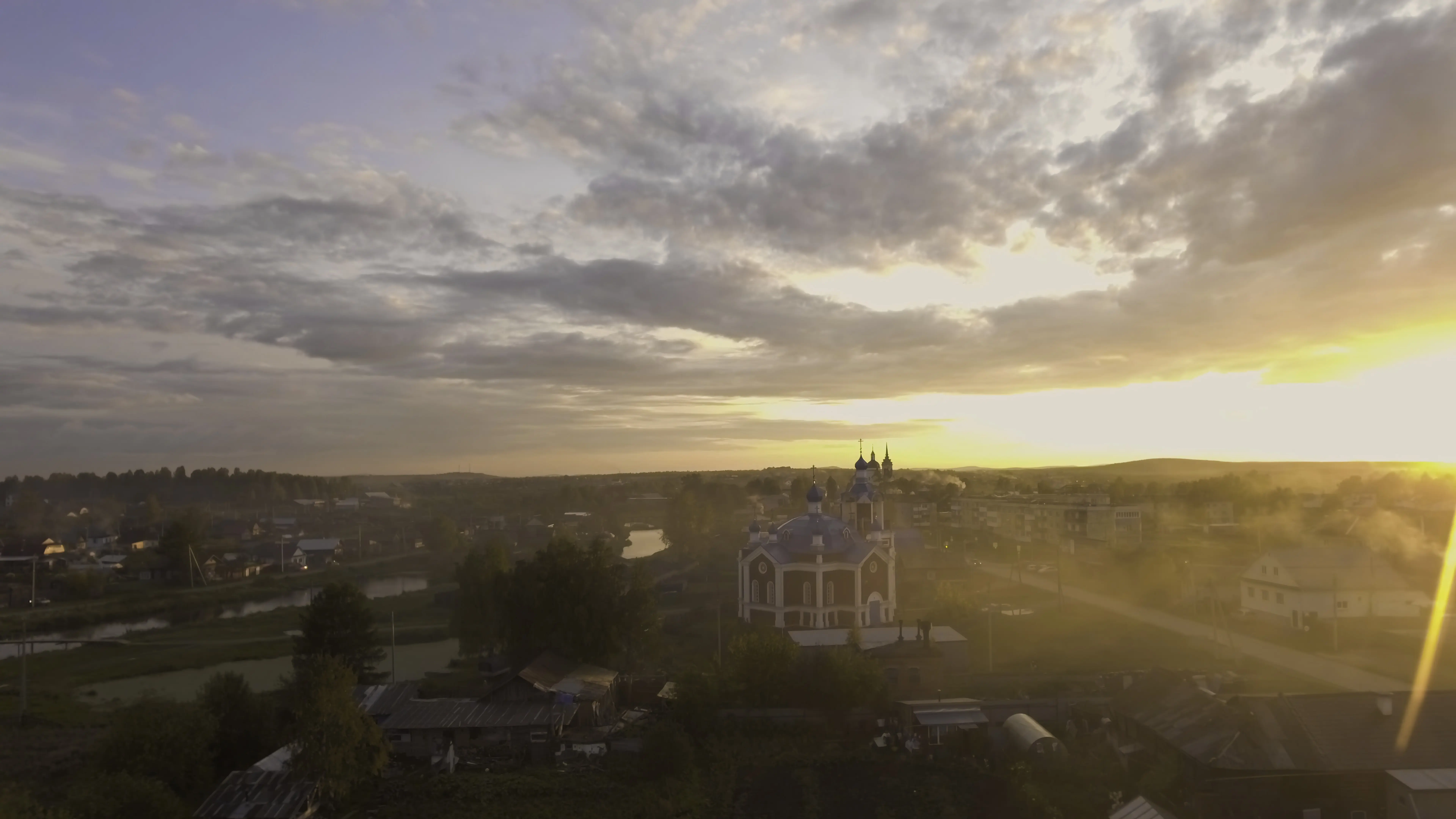 Stockaufnahme: Schöne Draufsicht einer russischen Kirche in den Strahlen der untergehenden Sonne vor dem Hintergrund einer Stadt.